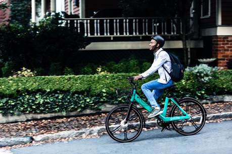 A person riding a bicycle in front of a building Description automatically generated